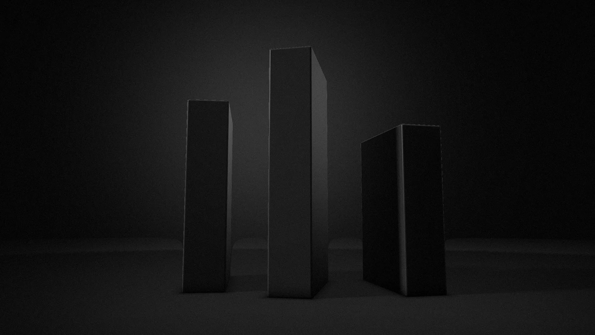 Three dark monoliths standing in low side light